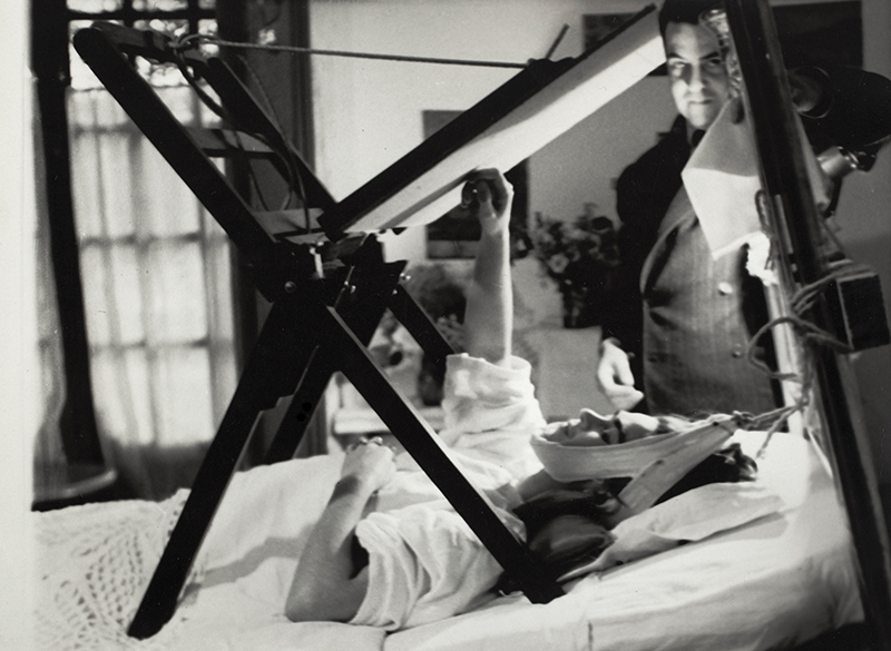 Frida målar i sängen, anonym, 1940. Miguel Covarrubias stående vid hennes sida. Diego Rivera & Frida Kahlo Archives