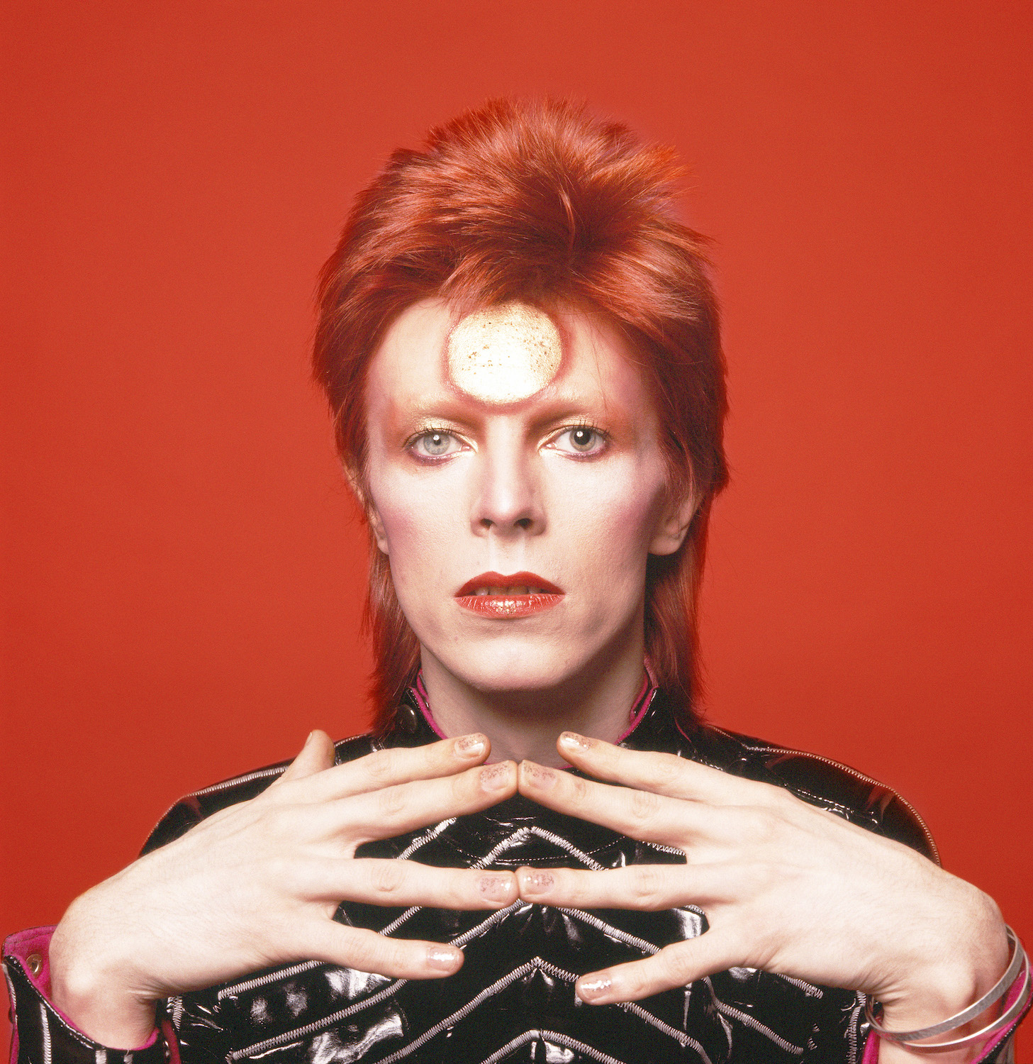 Artisten David Bowie med rött hår mot en röd bakgrund. 