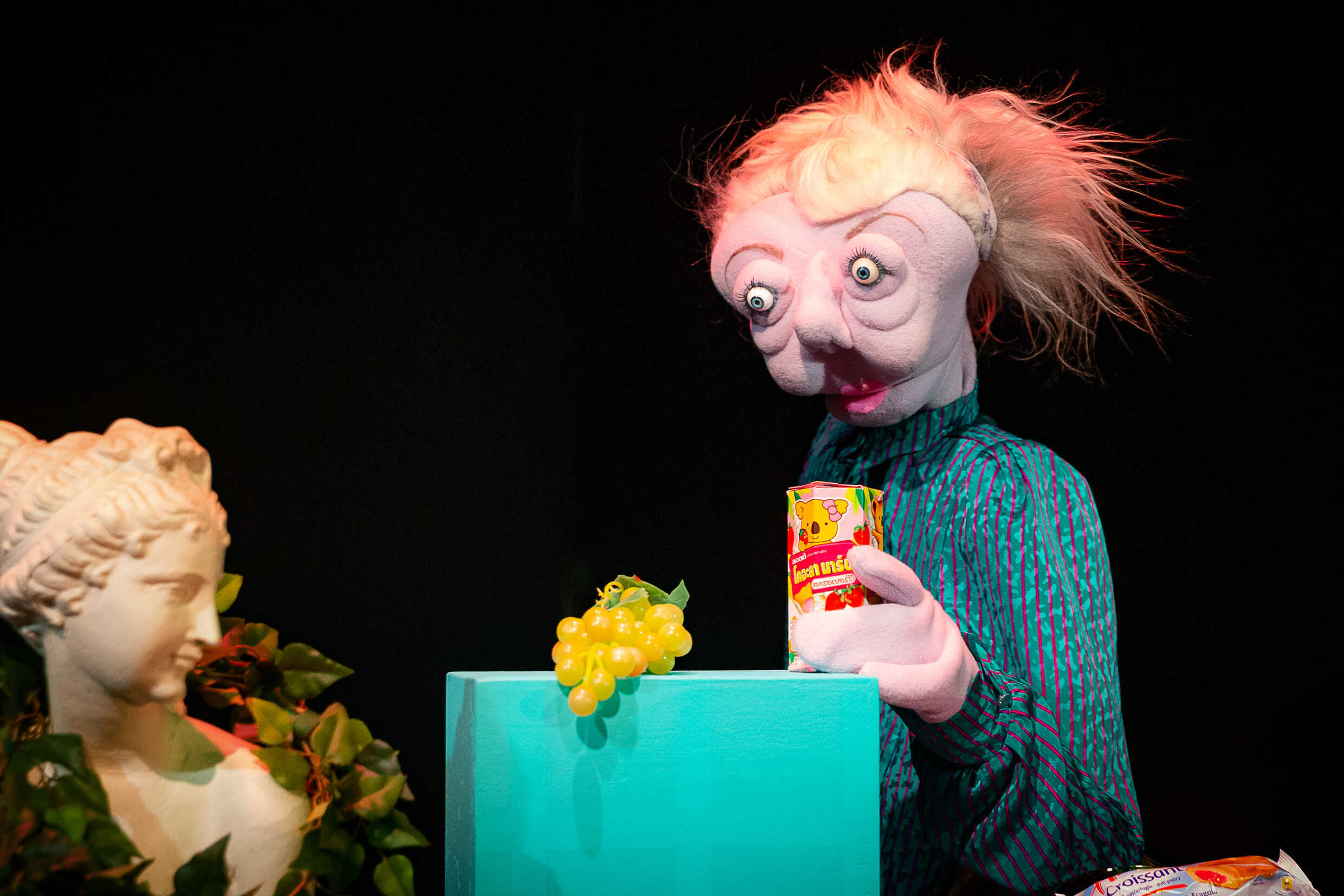 En docka med stirrig blick håller i ett paket med juice. 