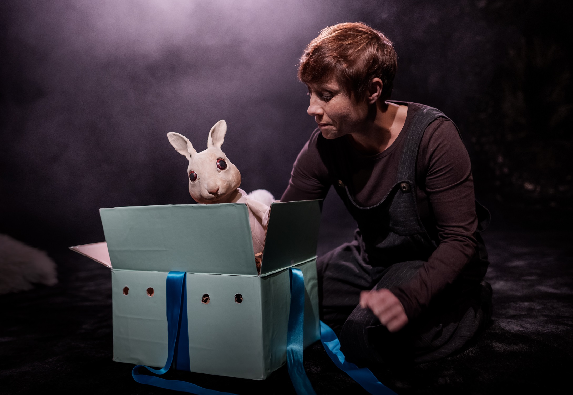 En kvinna tittar på en kanindocka som kommer upp ur en låda. 