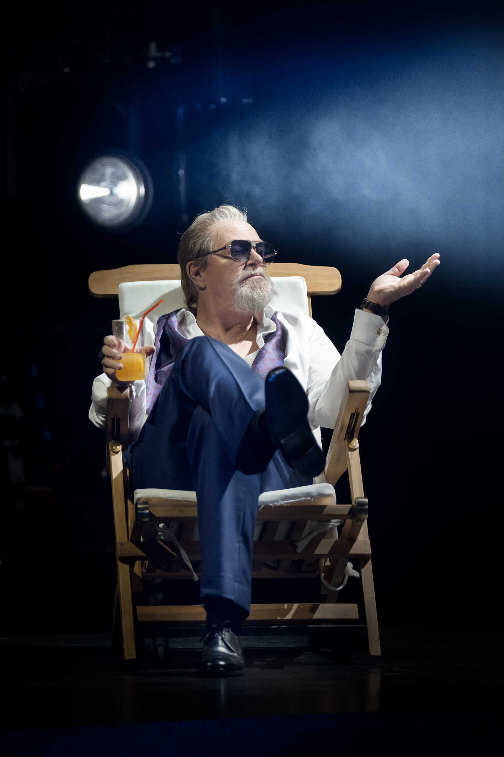 En man sitter tillbakalutad i en stol med en drink i handen. 