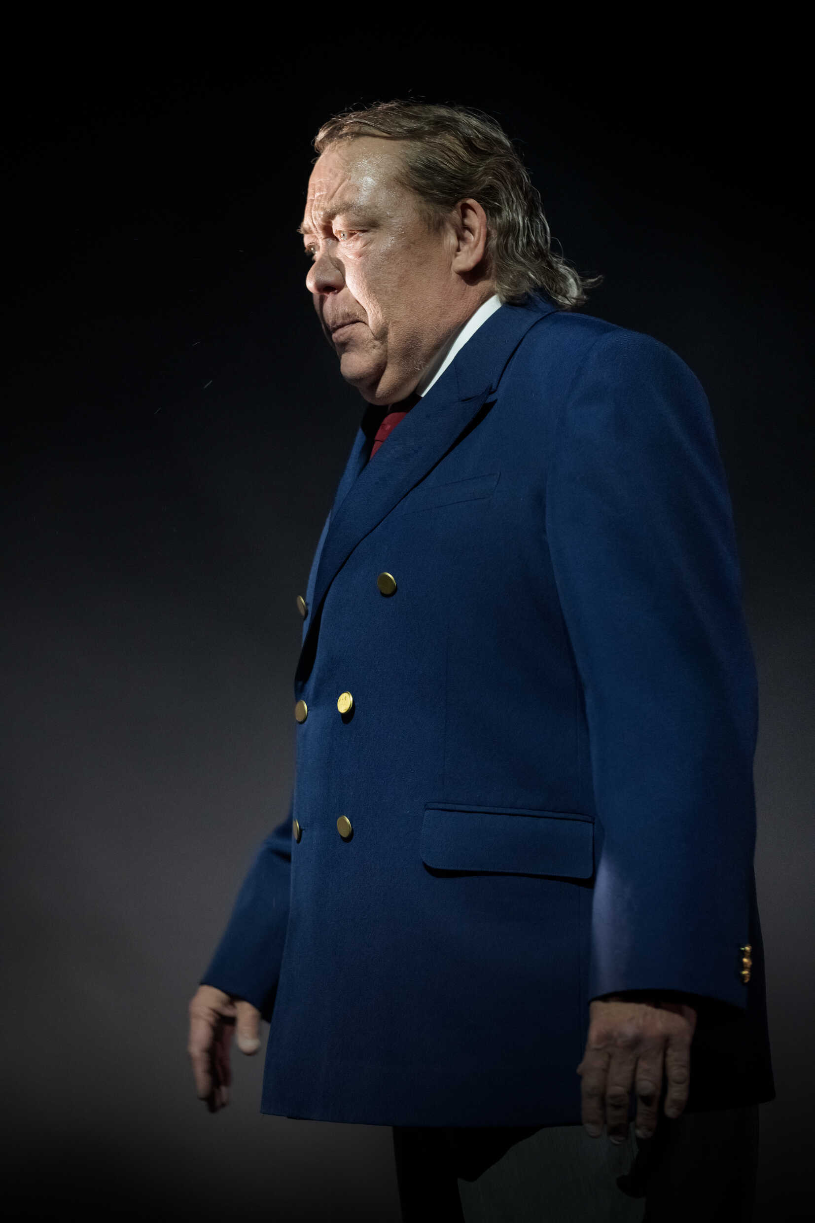 En man i mörkblå kostym på scen. 