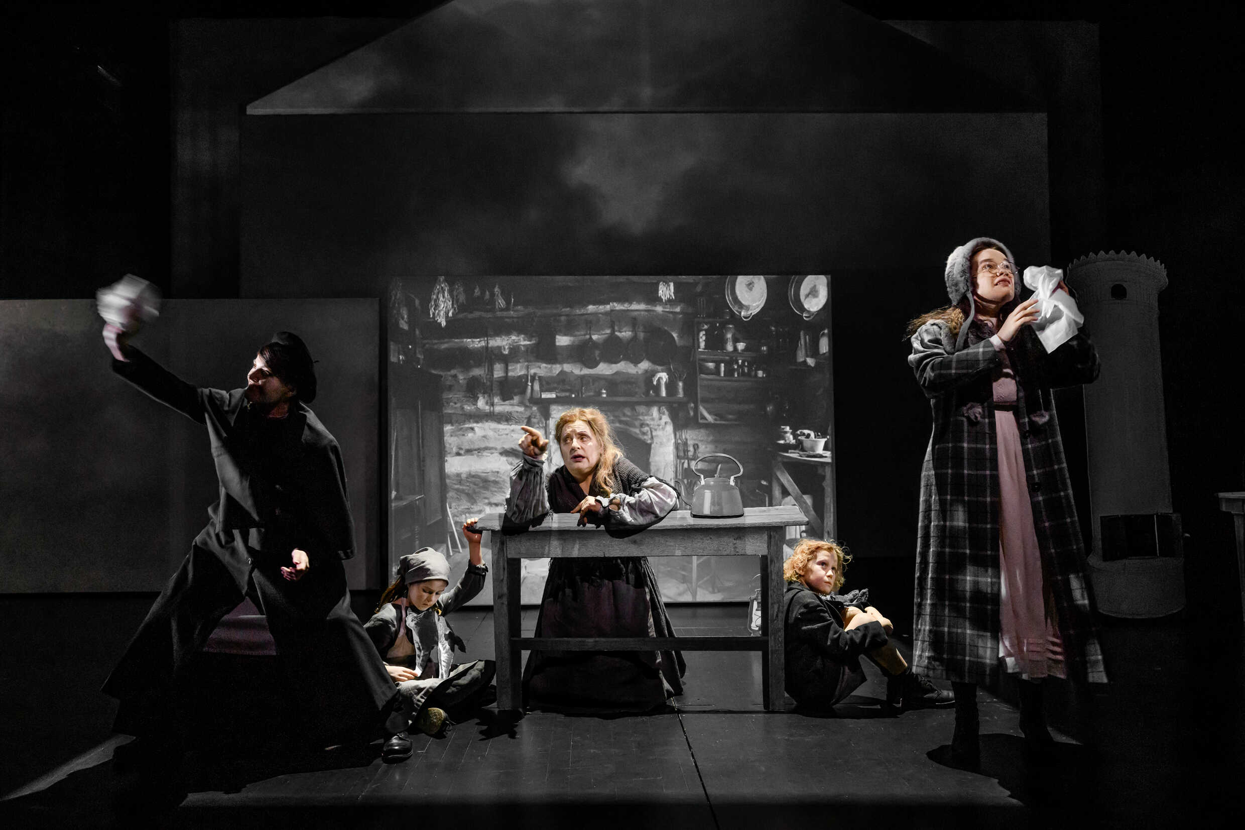Fem skådespelare, både barn och vuxna, på scenen i pjäsen Skuggan över stenbänken. 