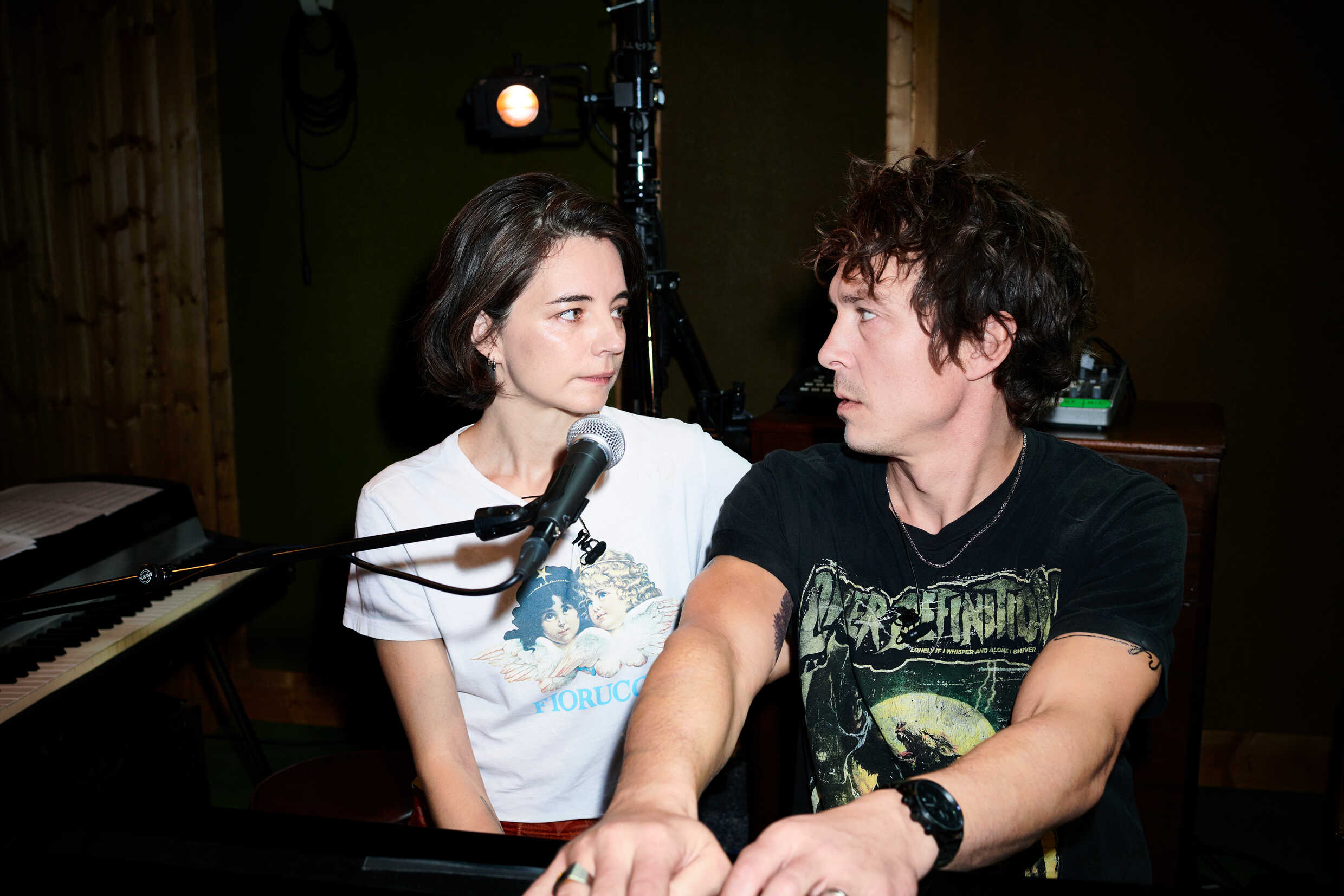 En kvinna och en man tittar på varandra och sjunger i en mikrofon tillsammans. 