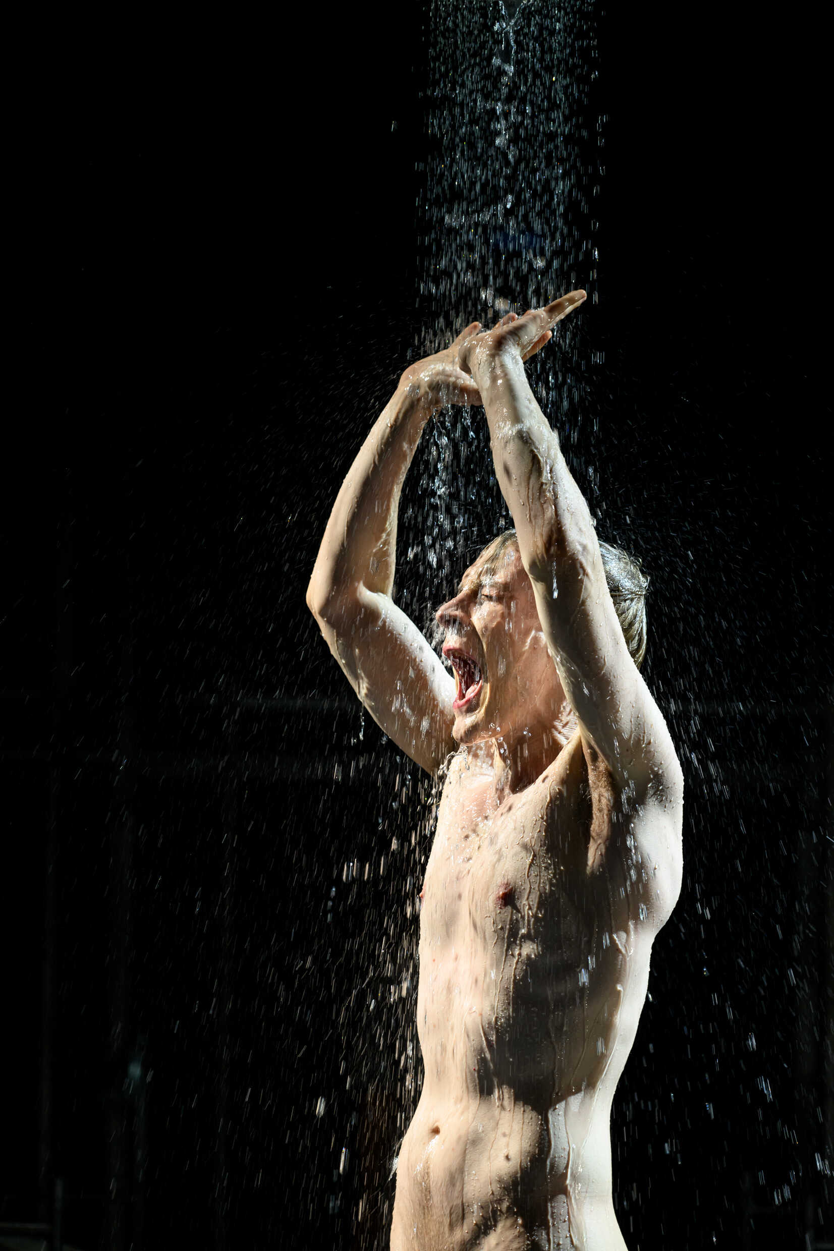 En skådespelare på scen får vatten över sig. 
