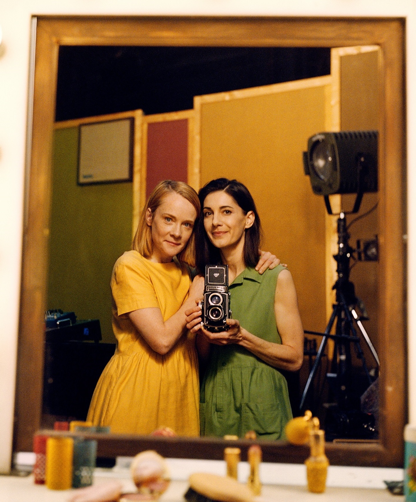 Två kvinnor fotograferar sig själva i en spegel med en kamera av äldre modell. 