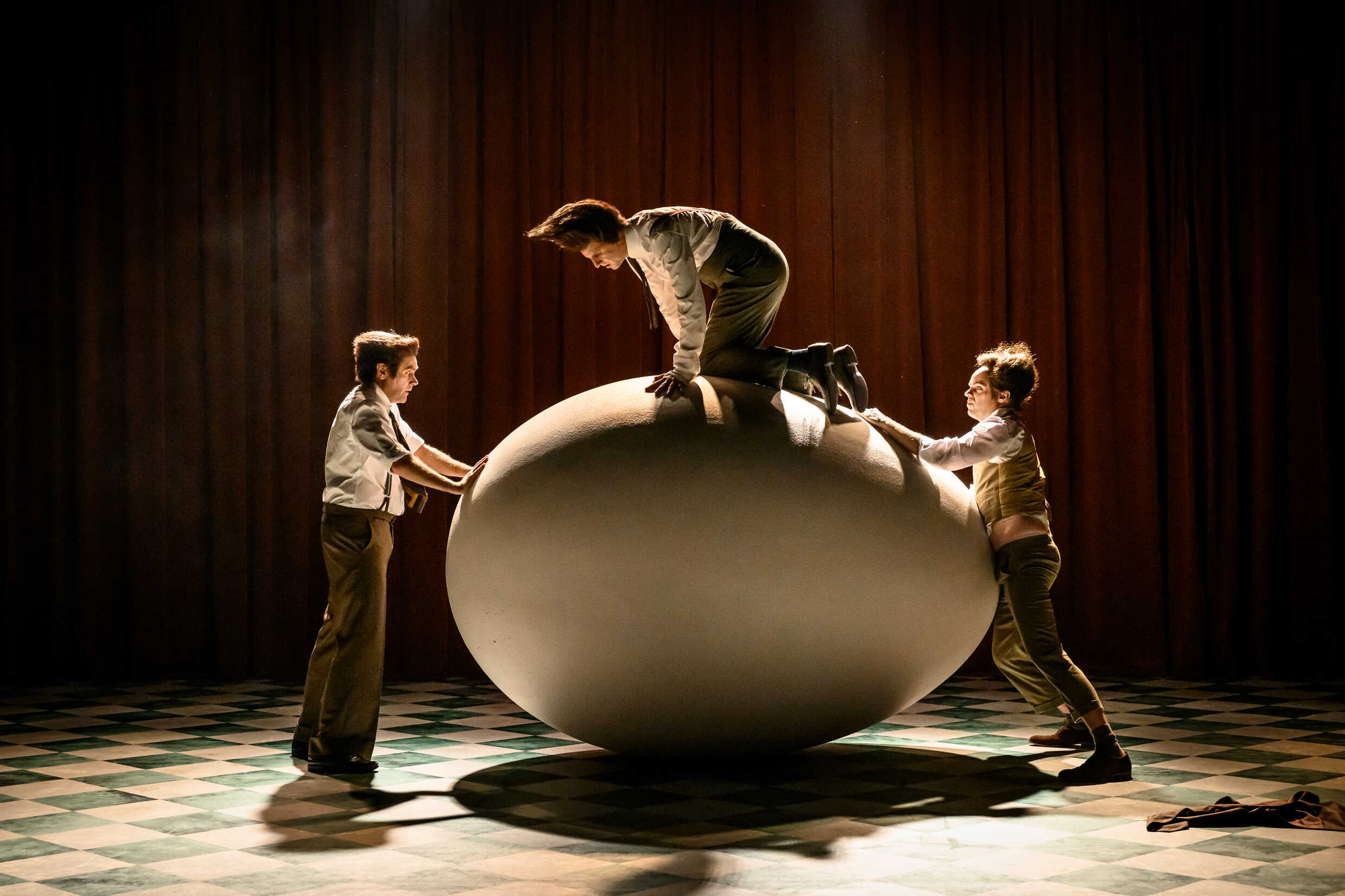 Tre skådespelare och ett stort ägg på en scen. 