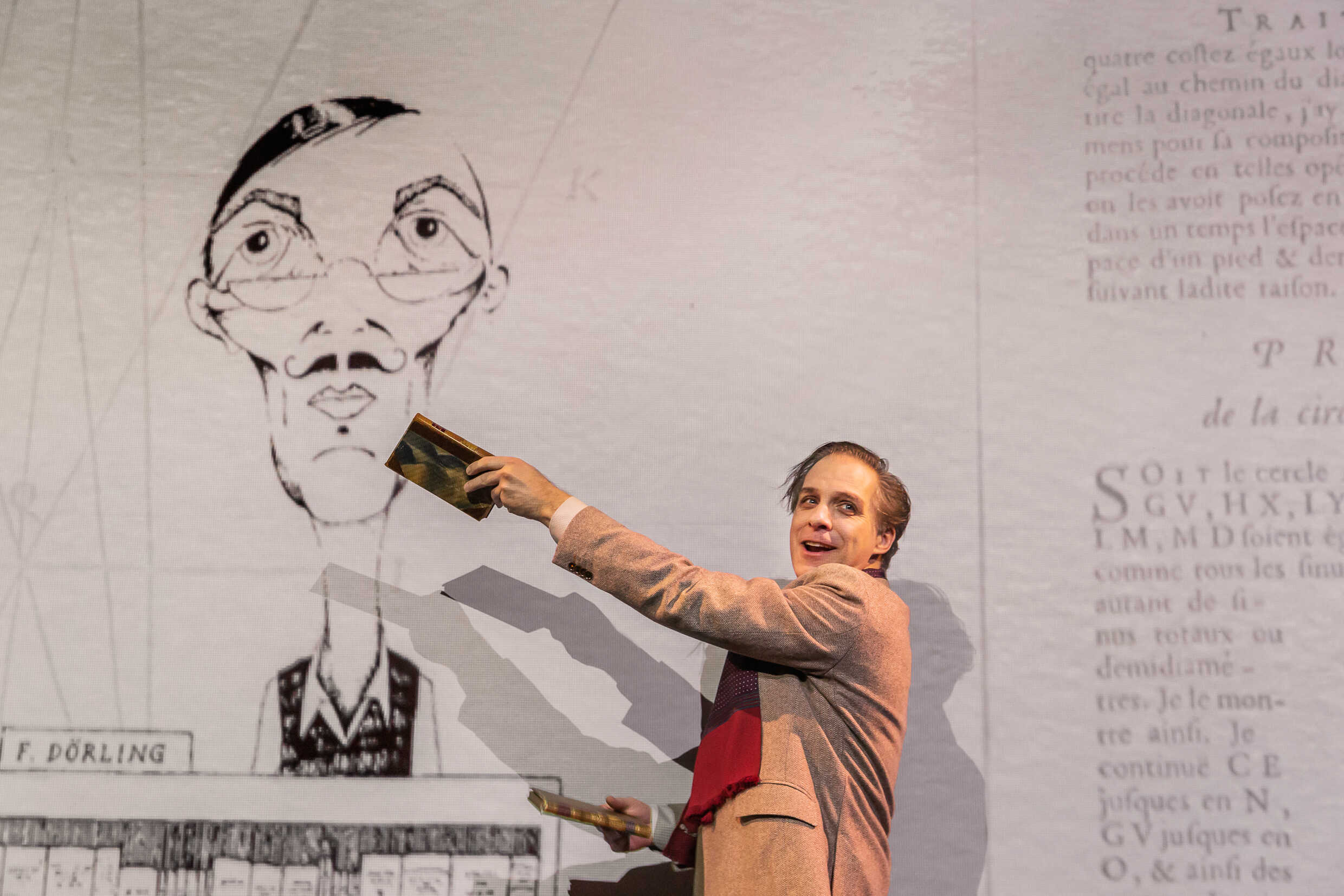 Fredrik Meyer med en bok handen framför en teckning föreställande en bokförsäljare