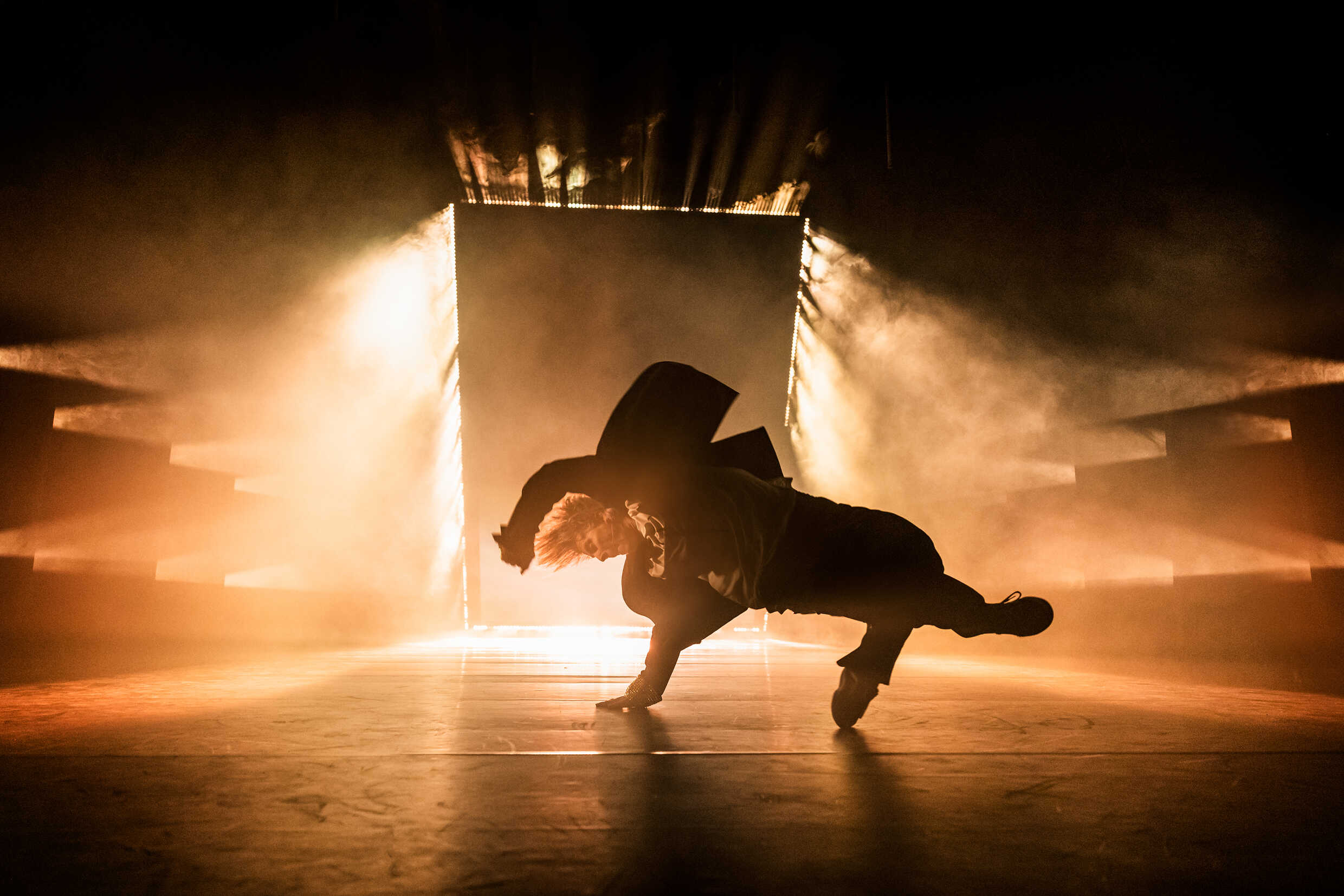 En dansare dansar på en scen upplyst i guldfärg. 