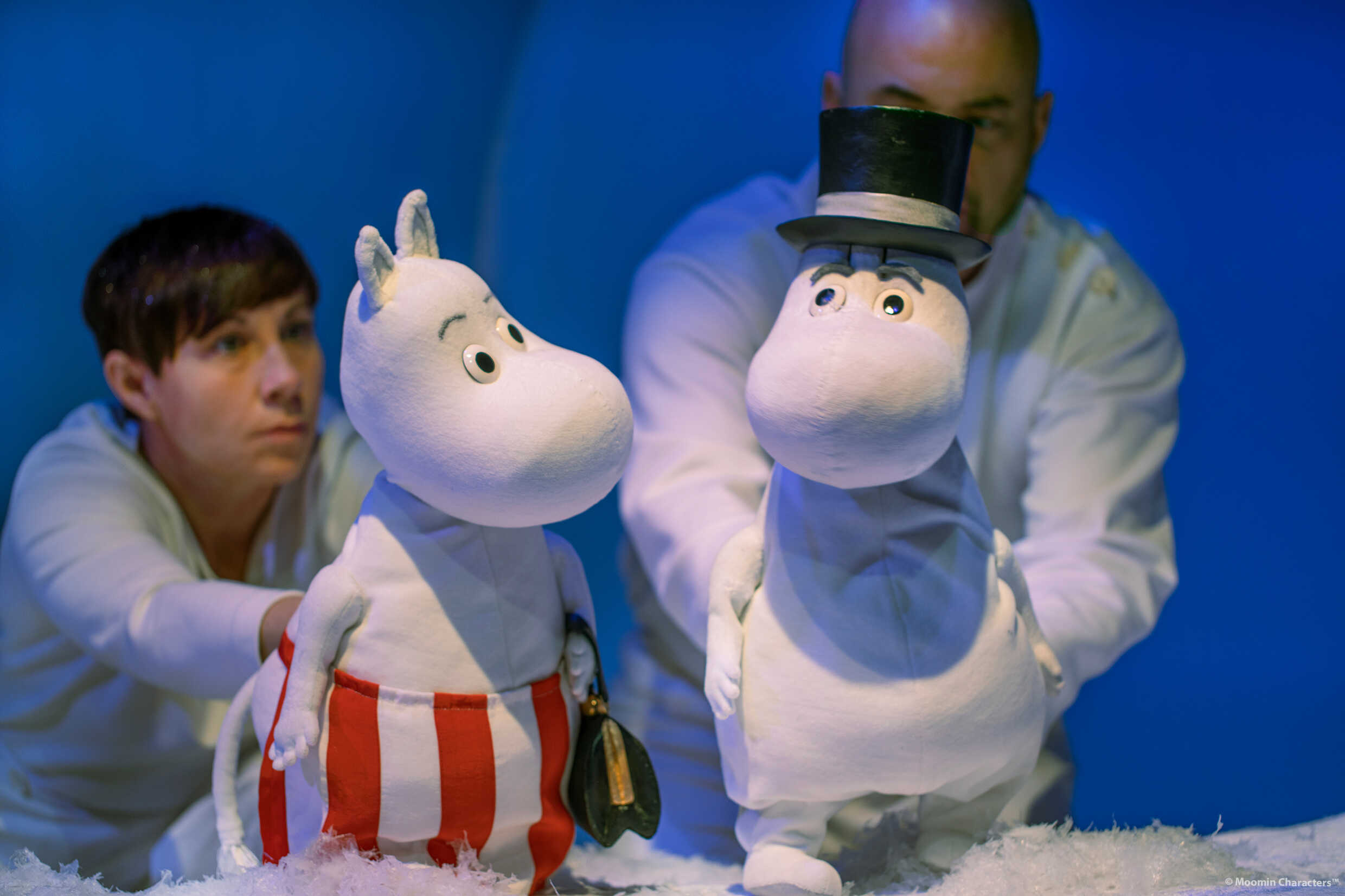 Två dockskådespelare håller i mumintroll i föreställningen Granen på Marionetteatern. 